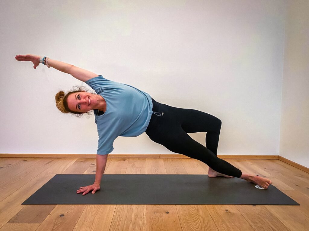 Sissi in Action auf ihrer Yogamatte in einer Seitlichen Planke, sie lächelt in die Kamera